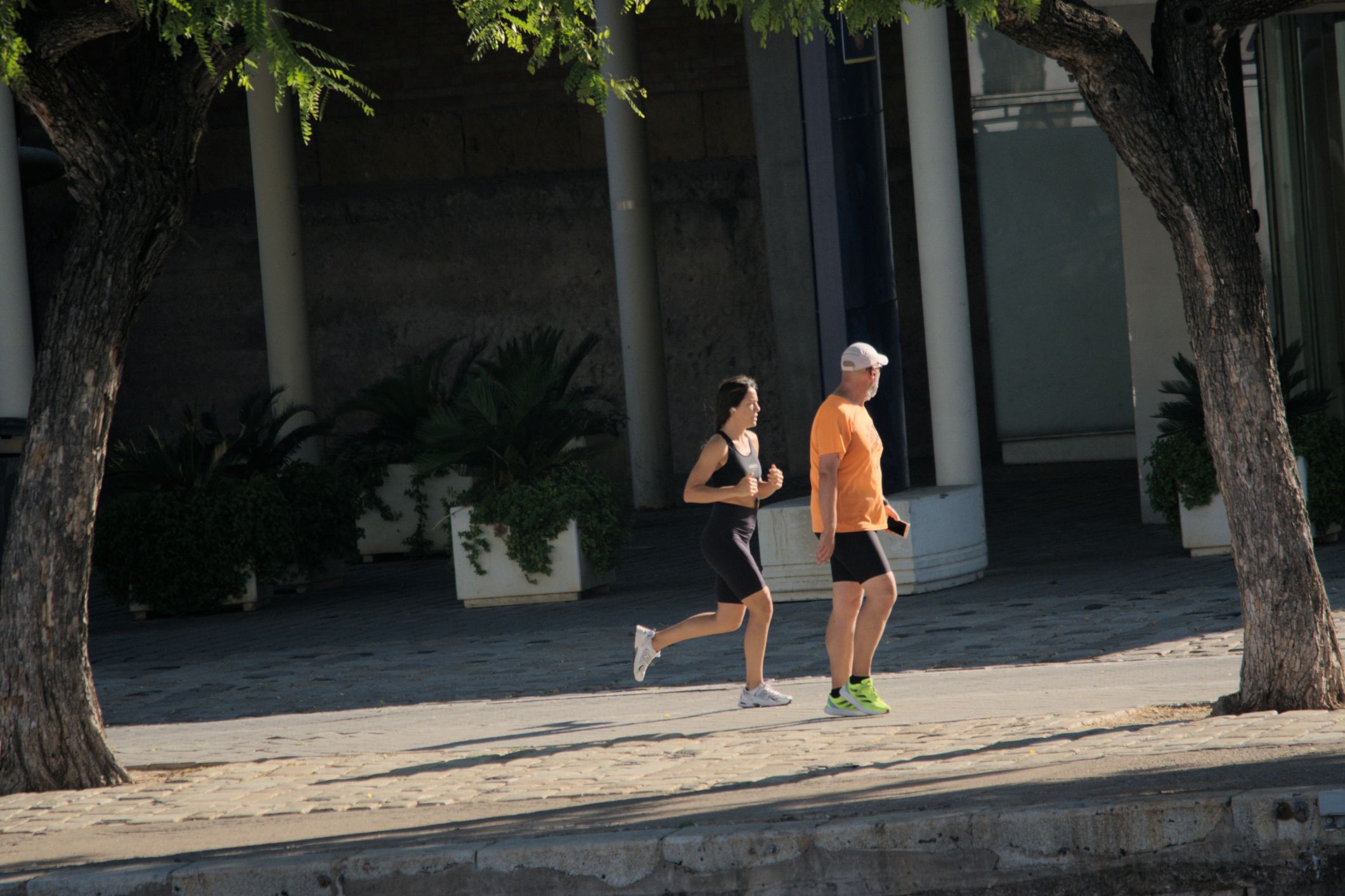 A man and a woman jogging outdoors in casual athletic wear.